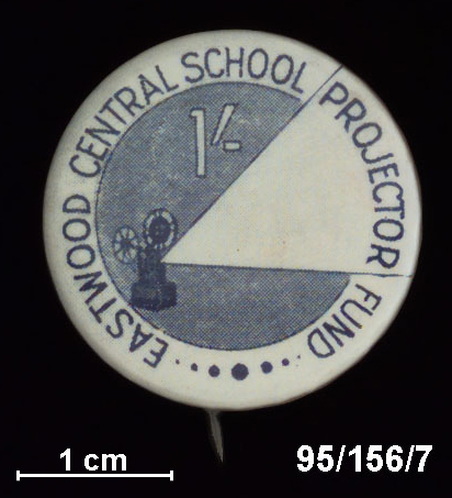 A round metal badge with a pin at the back to attached to clothing.